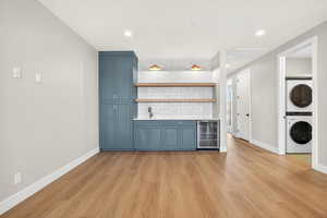 Kitchen featuring backsplash, beverage cooler, open shelves, light wood-style flooring, and recessed lighting