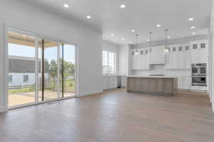 Kitchen featuring white cabinets, glass insert cabinets, recessed lighting, light wood-style flooring, and appliances with stainless steel finishes