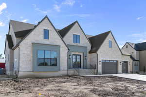 French country home featuring stone siding, driveway, french doors, roof with shingles, and a garage
