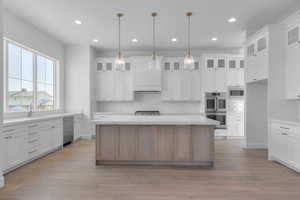 Kitchen featuring white cabinetry, recessed lighting, stainless steel appliances, glass insert cabinets, and a kitchen island