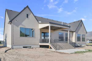 Back of house with a patio and roof with shingles