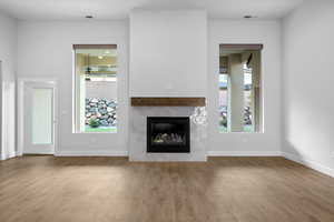 Unfurnished living room featuring a tile fireplace and wood finished floors