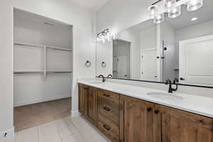 Bathroom with light carpet, light tile patterned floors, double vanity, and a walk in closet