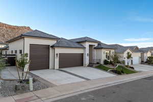 View of front of house featuring stucco siding, a garage, and driveway