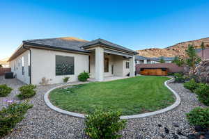 Rear view of house with a fenced backyard, stucco siding, a patio, a ceiling fan, and a hot tub