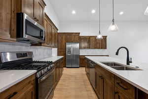 Kitchen with appliances with stainless steel finishes, decorative backsplash, light stone counters, and recessed lighting