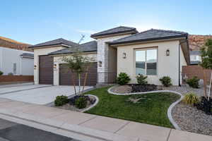 View of front of property with stucco siding, a garage, driveway, a mountain view, and stone siding