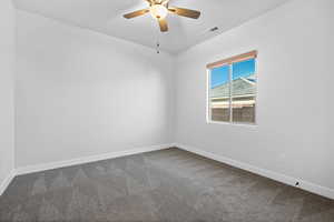 Carpeted spare room featuring baseboards and ceiling fan