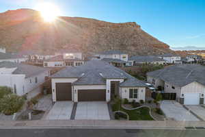 View of front of property with a garage, concrete driveway, stucco siding, a residential view, and a mountain view