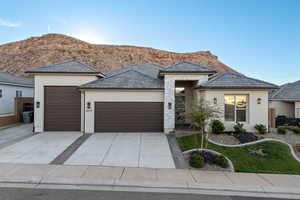 View of front of property with an attached garage, stucco siding, driveway, and a mountain view
