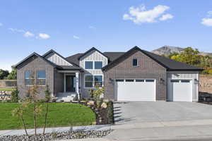 View of front facade with board and batten siding, a front lawn, driveway, an attached garage, and brick siding