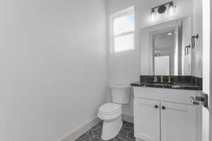 Half bathroom featuring vanity and dark tile patterned flooring