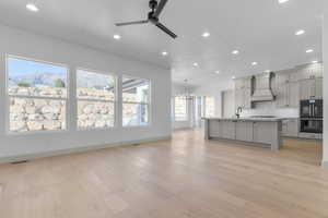 Kitchen featuring gray cabinets, recessed lighting, decorative backsplash, a center island with sink, and light wood-style flooring