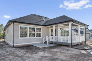 Rear view of property featuring roof with shingles, a patio area, and a deck
