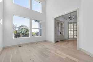 Entrance foyer with a chandelier, french doors, light wood-type flooring, and a high ceiling