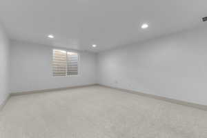 Carpeted spare room with baseboards and recessed lighting