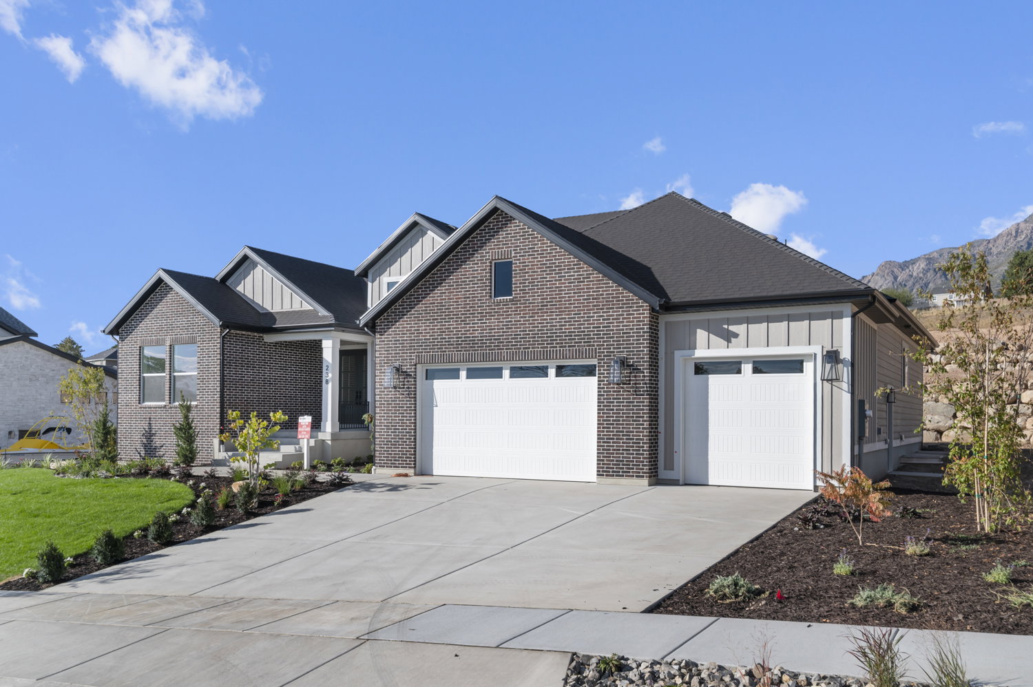 Craftsman inspired home with board and batten siding, a garage, concrete driveway, and brick siding