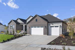 Craftsman inspired home with board and batten siding, a garage, concrete driveway, and brick siding