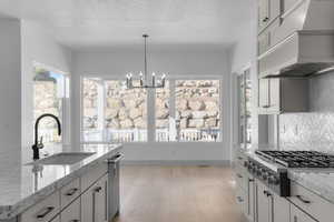 Kitchen featuring premium range hood, stainless steel appliances, plenty of natural light, a chandelier, and a textured ceiling
