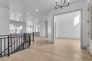 Hall with a chandelier, an upstairs landing, recessed lighting, and light wood-type flooring