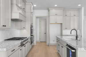 Kitchen with backsplash, white cabinetry, light wood-type flooring, stainless steel appliances, and recessed lighting
