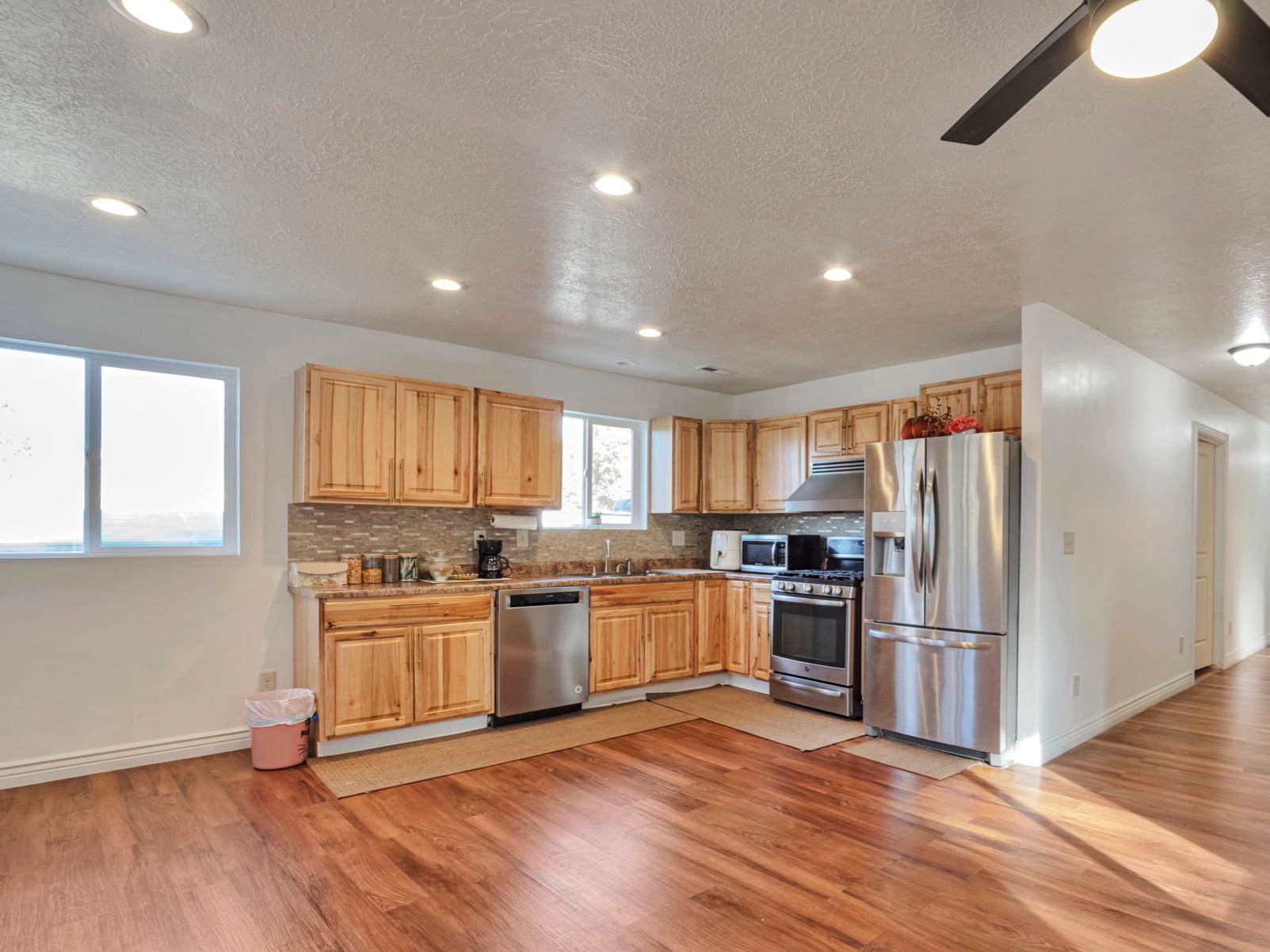 Kitchen featuring appliances with stainless steel finishes, tasteful backsplash, a textured ceiling, light wood finished floors, and recessed lighting