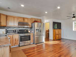 Kitchen featuring appliances with stainless steel finishes, recessed lighting, light wood-type flooring, open floor plan, and a desk