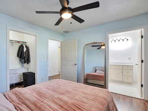 Bedroom featuring wood finished floors, a closet, ceiling fan, and connected bathroom