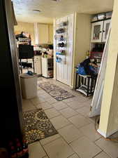 Laundry room featuring a textured ceiling and light tile patterned floors