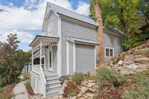 View of side of property featuring a metal roof and covered porch