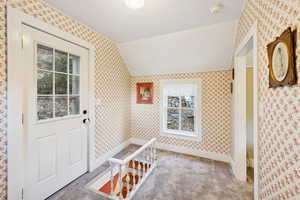 Mudroom featuring wallpapered walls, lofted ceiling, and carpet floors