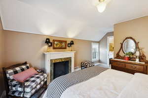 Bedroom featuring vaulted ceiling and a fireplace