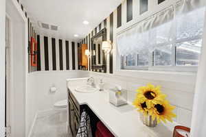 Bathroom with wallpapered walls, vanity, recessed lighting, light tile patterned flooring, and a wainscoted wall