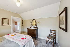 Bedroom with vaulted ceiling and carpet floors