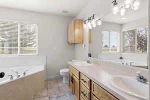 Full bath featuring a bath, double vanity, and light tile patterned floors