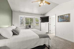 Bedroom with light carpet, ceiling fan, vaulted ceiling, and a textured ceiling