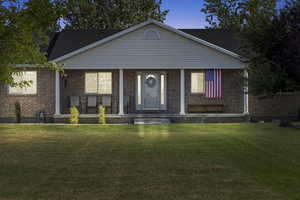 View of front facade featuring a porch, a yard, and brick siding