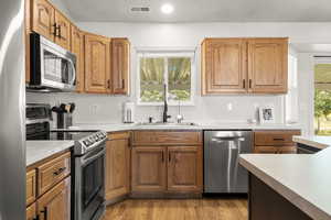 Kitchen featuring stainless steel appliances, healthy amount of natural light, light wood-style flooring, light countertops, and recessed lighting