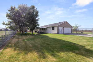 Fenced backyard featuring a patio area, driveway, and an attached garage