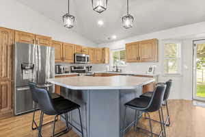 Kitchen featuring vaulted ceiling, hanging light fixtures, appliances with stainless steel finishes, light wood-type flooring, and recessed lighting