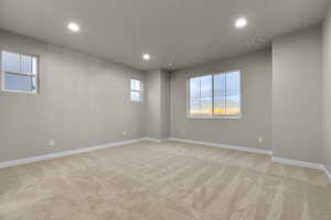 Empty room featuring light carpet, recessed lighting, and healthy amount of natural light