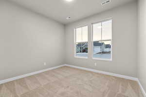 Spare room with baseboards and light colored carpet