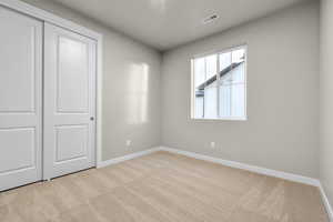 Unfurnished bedroom with light colored carpet and a closet
