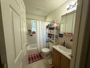 Full bathroom with a textured ceiling, shower / bath combination with curtain, and vanity