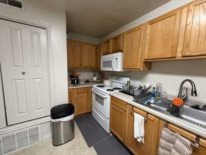 Kitchen with white appliances, light countertops, and brown cabinets