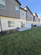 Rear view of property featuring a patio area and an open green space