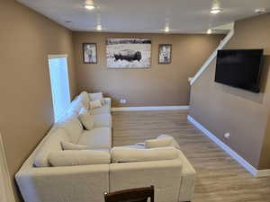 Living area with light wood colored finished floors and recessed lighting