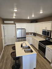 Kitchen featuring appliances with stainless steel finishes, white cabinetry, a kitchen island bar and access to 2 car garage