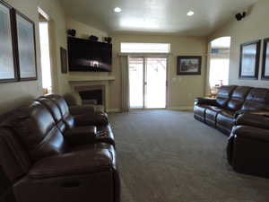 Carpeted living area featuring a tiled fireplace, plenty of natural light, and recessed lighting