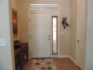 Foyer entrance with dark tile patterned floors and baseboards